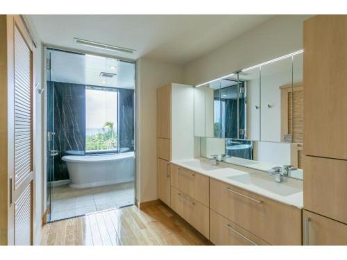 uma casa de banho com 2 lavatórios, uma banheira e um espelho. em Miyakojima Kurima Resort Seawood Hotel - Vacation STAY 16225v em Uechi