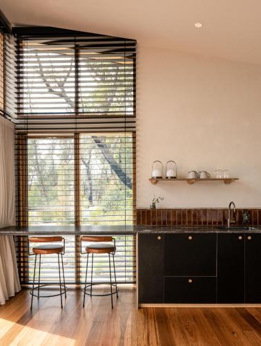 a kitchen with black cabinets and stools in front of a window at Chalets at Blackheath in Blackheath