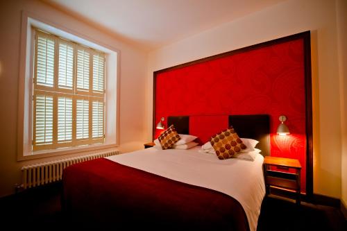 een slaapkamer met een groot bed met een rood hoofdeinde bij Tannery Townhouse in Dungarvan