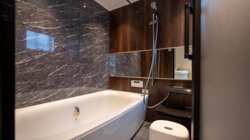 ein Bad mit einer Badewanne und einem WC in der Unterkunft trive ozone - Vacation STAY 25323v in Nagoya