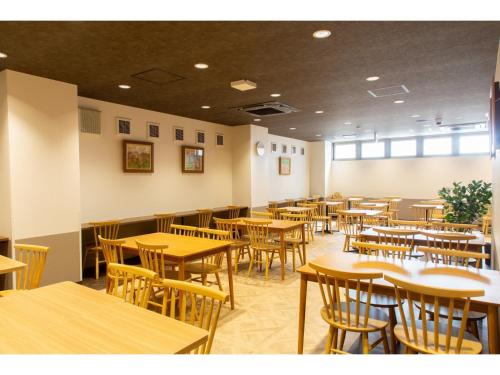 un ristorante vuoto con tavoli e sedie in legno di Hotel Taiyonoen Tokushima Kenchomae - Vacation STAY 26351v a Tokushima