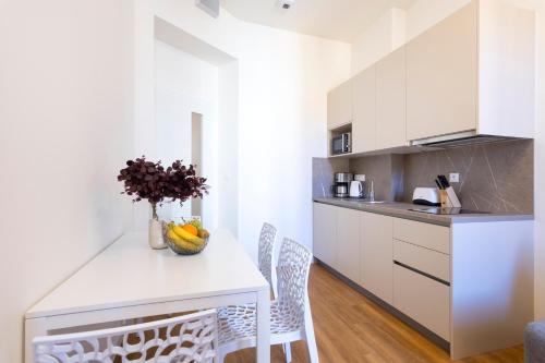 a kitchen with white cabinets and a table and chairs at Hidden Art Boutique Residence by Dwellfort in Prague
