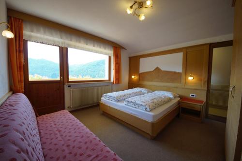 a bedroom with two beds and two windows at Cresta in San Cassiano