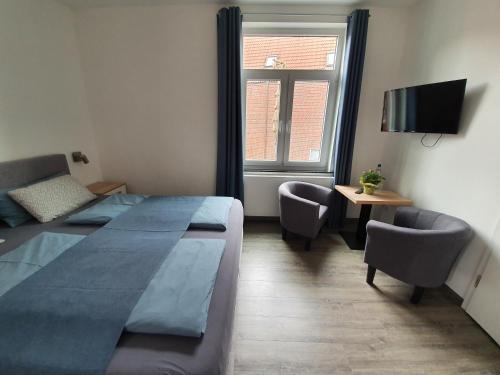 a bedroom with a bed and two chairs and a television at Inselkern Einraum-Apartments in Juist