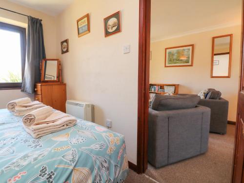 a bedroom with a bed and a chair at Honeysuckle Cottage in Bude