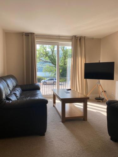 a living room with a couch and a coffee table at Borrodale, one bedroom apartment with balcony and loch view. in Fort William