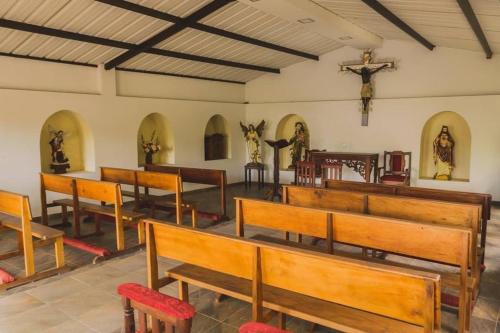 a church with wooden benches and a cross on the wall at Hotel Manantial in Buga