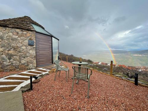 a bench and a table with a rainbow in the background at Glamping El Regajo Valle del Jerte in El Torno