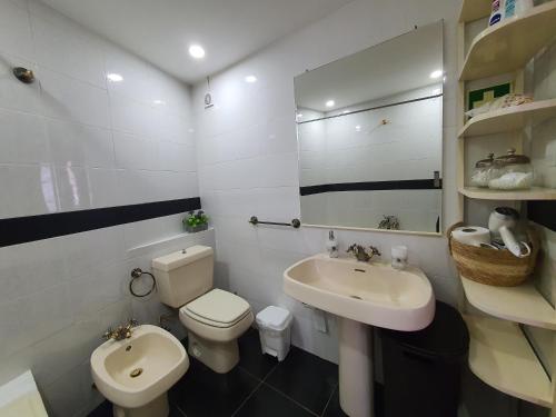 a white bathroom with a toilet and a sink at Casa Baleia á Vista in São Vicente Ferreira