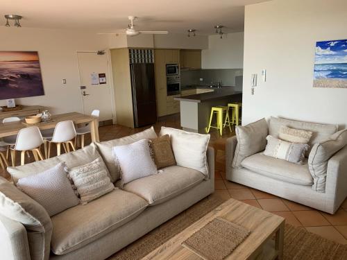a living room with two couches and a kitchen at Aqua Promenade Beachfront Holiday Apartments in Sunrise Beach