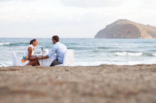 a man and a woman sitting on the beach at Thalassa Beach Resort & Spa (Adults Only) in Agia Marina Nea Kydonias