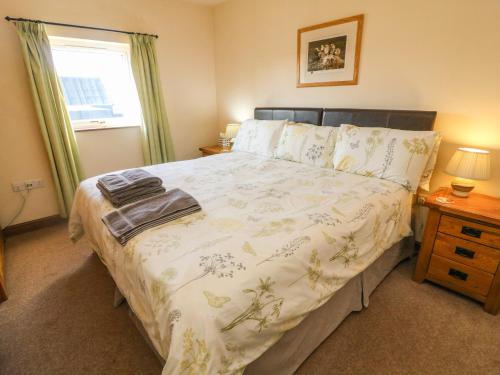 1 Schlafzimmer mit einem Bett mit Blumenbettdecke und einem Fenster in der Unterkunft Bytheway Cottage in Ingleton 