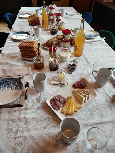 - une table avec des assiettes de nourriture et des bouteilles de jus d'orange dans l'établissement La Maison Forte, à Revigny-sur-Ornain