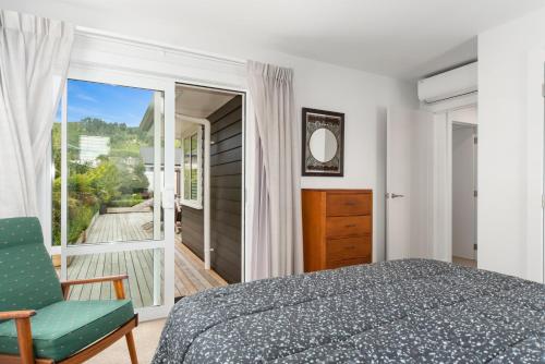 a bedroom with a bed and a chair and a balcony at Rogers Retreat - Kinloch Holiday Home in Kinloch