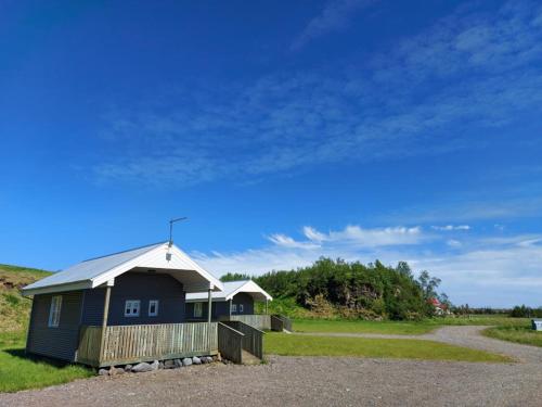 a blue house with a white roof on a field at Lækjaborgir Guesthouse in Kálfafell