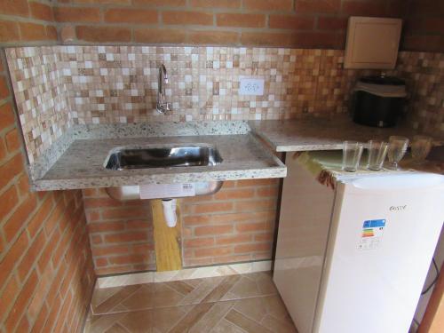 a kitchen counter with a sink and a refrigerator at CHALÉ Nativo R do Céu nº 106 in Conceição da Ibitipoca