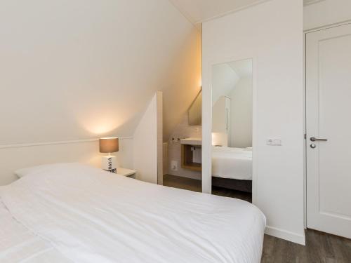 a white bedroom with a bed and a mirror at Villa in Friesland with Sauna and Whirlpool in Delfstrahuizen