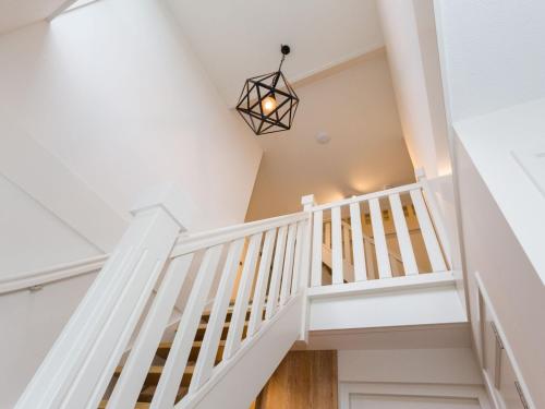 a white staircase in a house with a chandelier at Villa in Friesland with Sauna and Whirlpool in Delfstrahuizen
