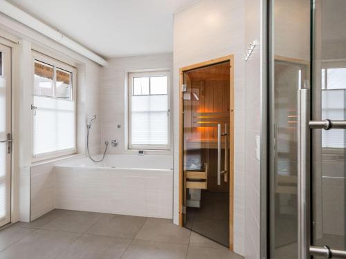 a bathroom with a bath tub and a shower at Villa in Friesland with Sauna and Whirlpool in Delfstrahuizen