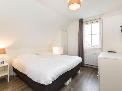 a bedroom with a white bed and a window at Villa in Friesland with Sauna and Whirlpool in Delfstrahuizen