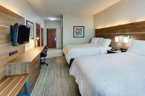 a hotel room with two beds and a flat screen tv at Holiday Inn Express & Suites Waxahachie by IHG in Waxahachie