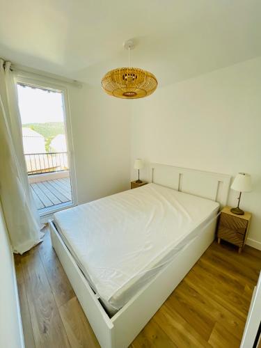 un lit blanc dans une chambre avec une fenêtre dans l'établissement Superbe T2 avec vue mer et piscine, à La Croix-Valmer