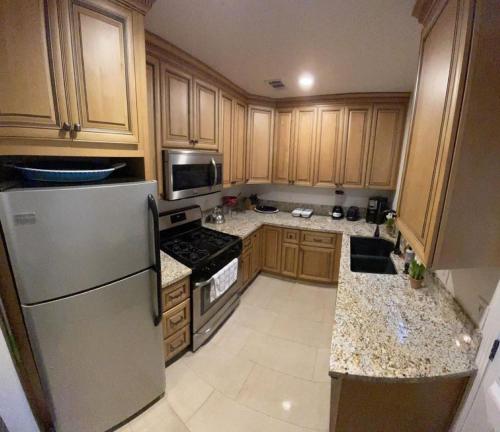 a kitchen with wooden cabinets and a stainless steel refrigerator at Luxury Suite near Universal Studios in Los Angeles