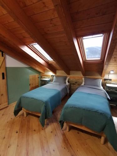 two beds in a room with wooden floors and a window at El Puente Peregrino in Trabadelo