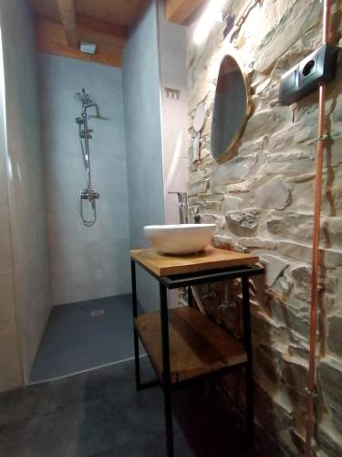 a bathroom with a sink and a stone wall at El Puente Peregrino in Trabadelo