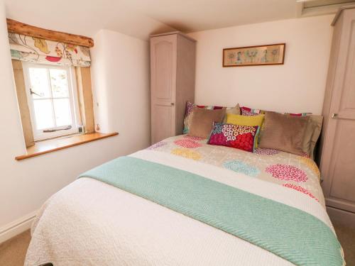 a bedroom with a bed with colorful pillows on it at Rose Cottage in Bakewell