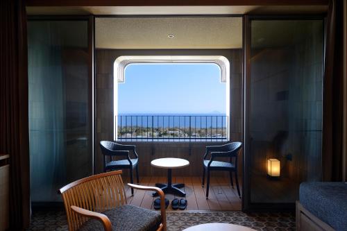 a room with a window with chairs and a table at KAMENOI HOTEL Izukogen in Ito