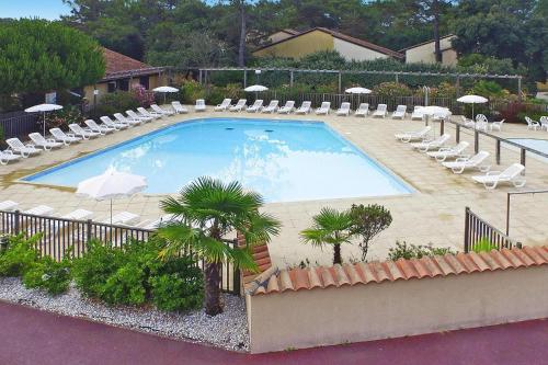 une grande piscine avec chaises longues et parasols dans l'établissement Gite for 8 guests in Medoc, à Soulac-sur-Mer