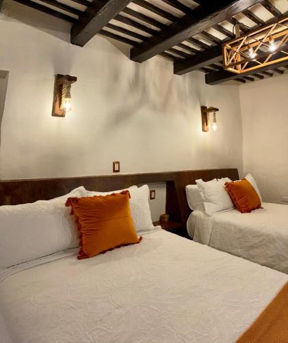 two beds with orange pillows in a room at Kuxtal Hotel Boutique in Mérida