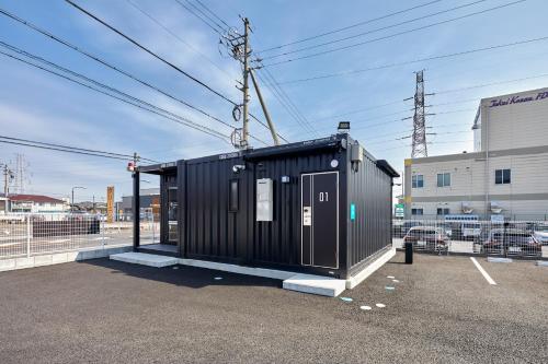 a black shed sitting in a parking lot at HOTEL R9 The Yard Tarui in Tarui