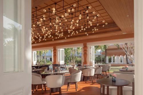 a restaurant with tables and chairs and a chandelier at The Pe La Resort, Phuket - SHA Extra Plus in Kamala Beach