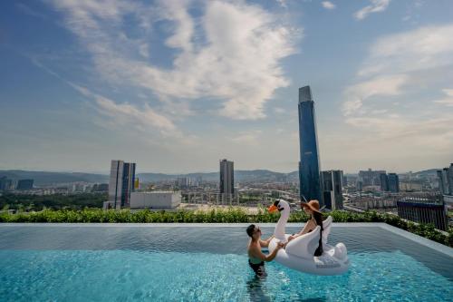 two people standing on a swimming pool with swans at Capri by Fraser, Bukit Bintang in Kuala Lumpur