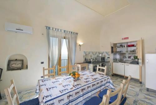 a dining room with a table and a kitchen at Terrazza di Rosa - sea view in Praiano