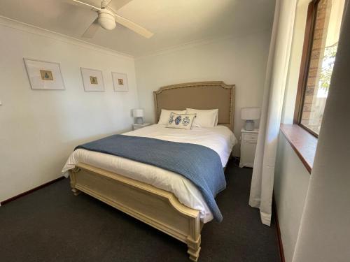 a bedroom with a bed with a blue blanket at Siroque Busselton in Busselton