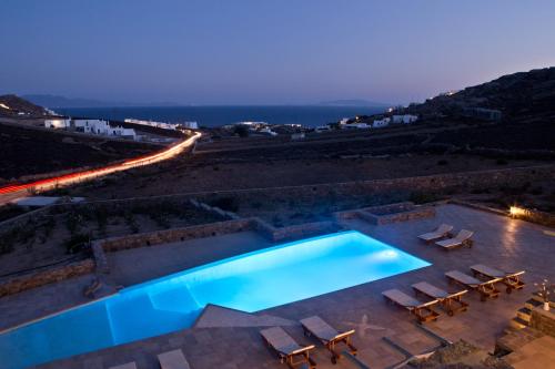 a swimming pool with chairs and the ocean at night at Niriides Homes & Villas in Elia Beach