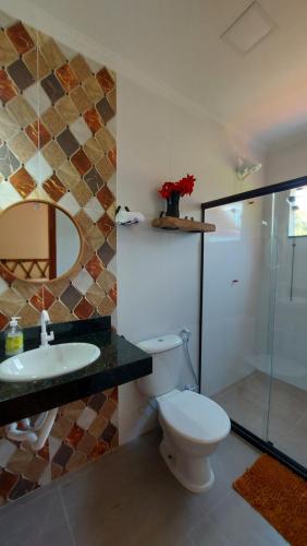 a bathroom with a toilet and a sink and a shower at Pousada Camping dos Ypês in Guapimirim