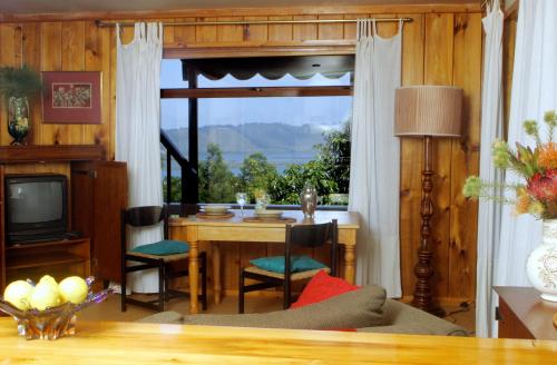 a living room with a table and a large window at Mount Joy Cottages in Knysna