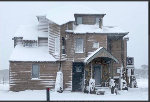 an old wooden house with snow on top of it at Barcoo Chalet, alpine-getaways. in Dinner Plain