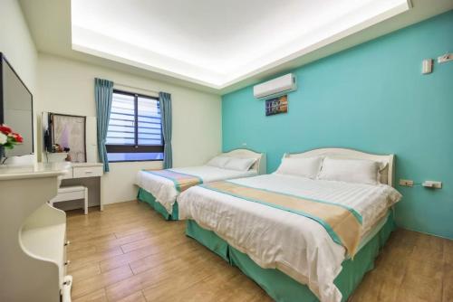 two beds in a room with blue walls and wooden floors at 客拉客民宿 Clock B&B in Huxi