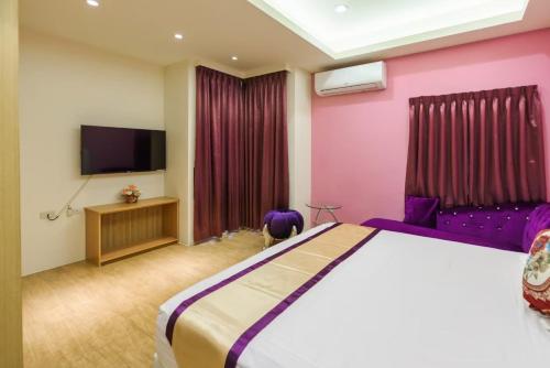 a bedroom with a large bed and a flat screen tv at 客拉客民宿 Clock B&B in Huxi