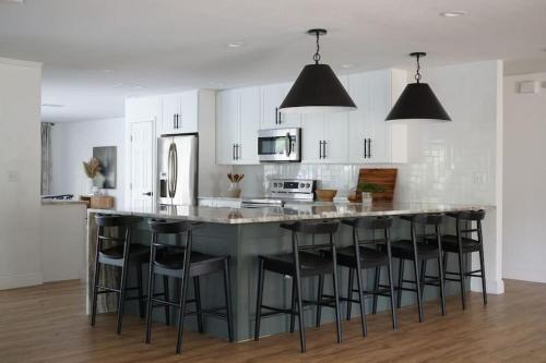 una cocina con armarios blancos y una gran isla con taburetes. en Remodeled 4BR Pool Home / Golf View/Near Beaches, en Sarasota