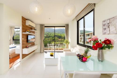 a living room with a glass table and flowers at LAGO APARTMENTS BY TROPICLOOK in Nai Harn Beach