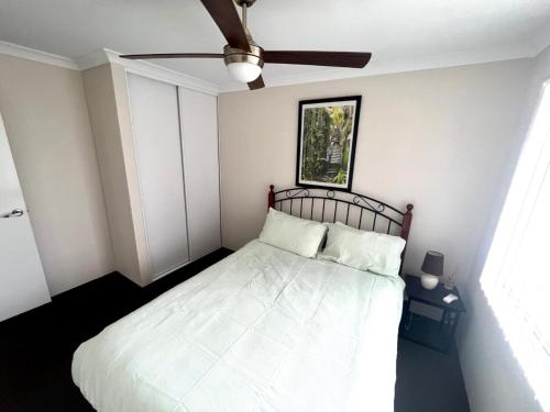 a bedroom with a white bed with a ceiling fan at Napolean Holiday Retreat in Vasse