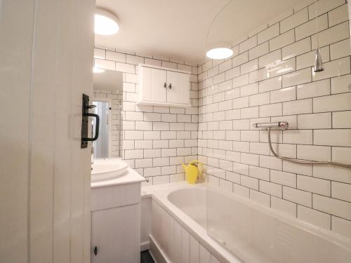 a white bathroom with a tub and a sink at River Cottage in Burton Bradstock