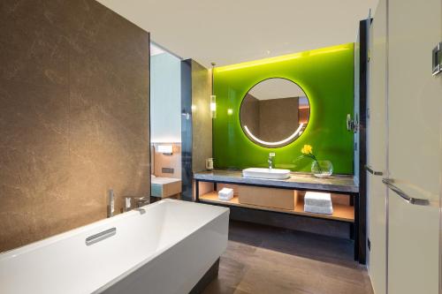 baño con bañera blanca y pared verde en Holiday Inn Zhengzhou High-Tech Zone by IHG, en Zhengzhou