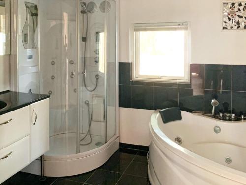 uma casa de banho com uma banheira, um chuveiro e um lavatório. em Three-Bedroom Holiday home in Rødby 14 em Rodbyhavn